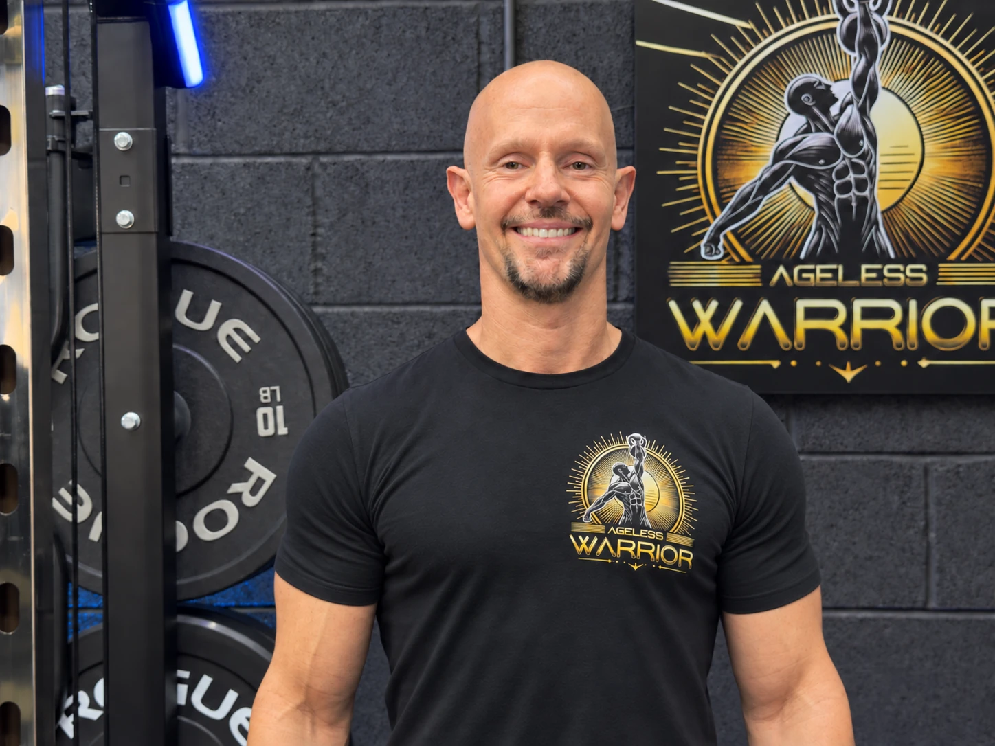Graham Harding smiling in his gym, wearing an Ageless Warrior T-shirt.